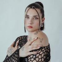 Frau mit Roségold-Creolen mit Perlen auf weißem Hintergrund