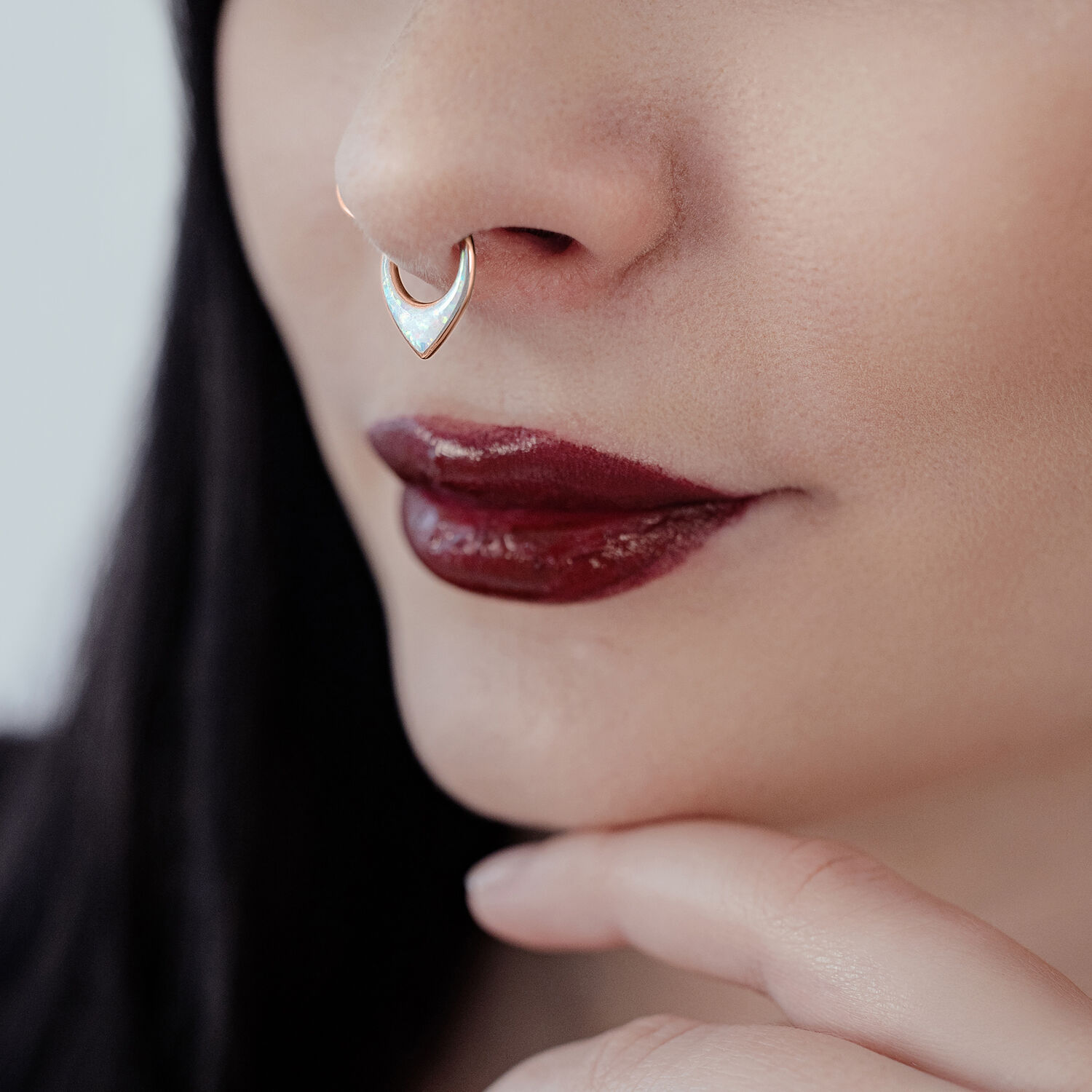 Lähikuva ruusukultaisesta septum clickeristä synteettisellä opaalilla nenässä