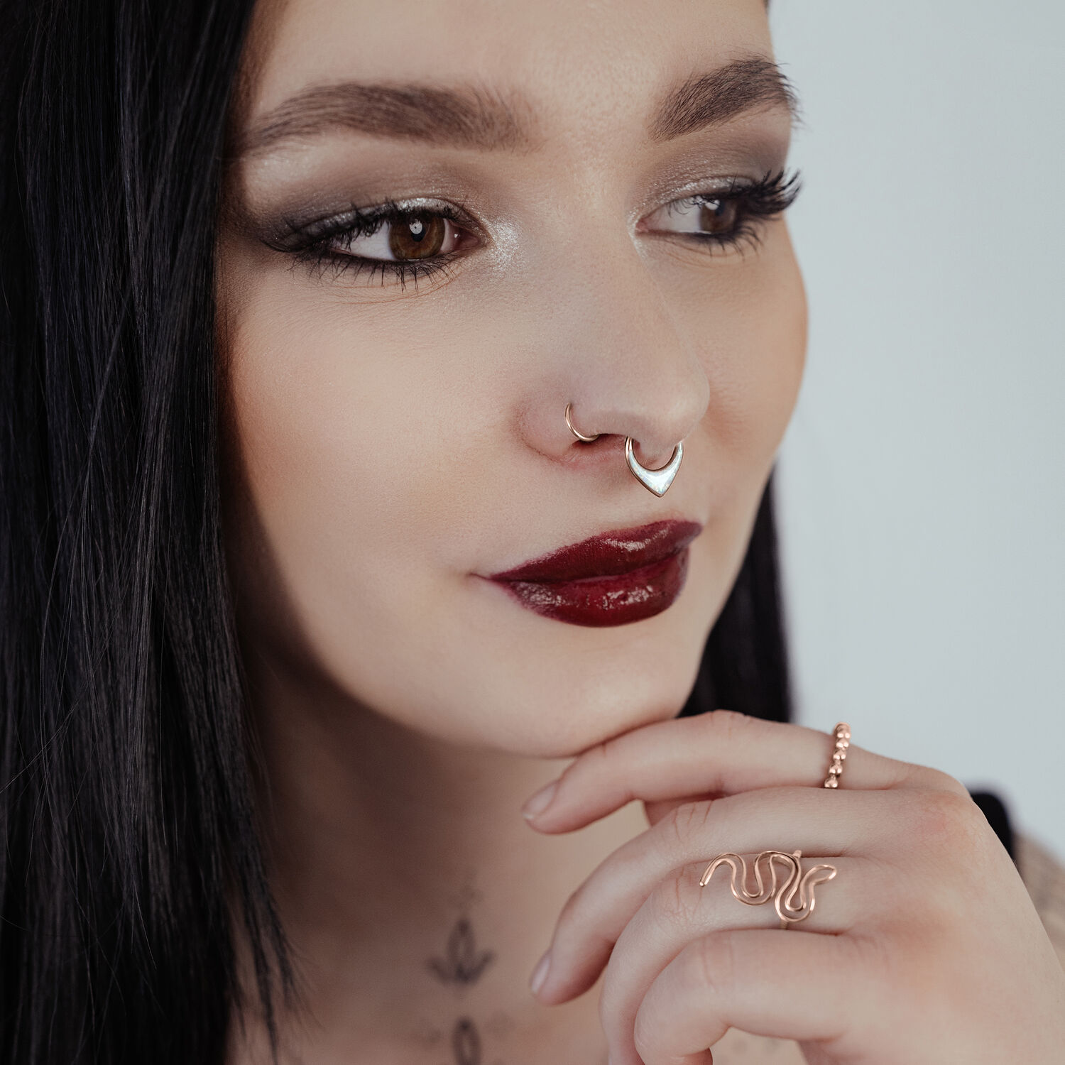 Nainen ruusukultaisella Chunky Synthetic Opal Septum Clickerilla vaaleaa taustaa vasten