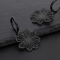 Schwarze Blumenohrringe aus Chirurgenstahl auf grauem Hintergrund