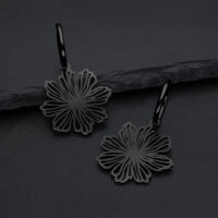 Schwarze Ohrringe in Blumenform aus Chirurgenstahl auf grauem Hintergrund