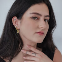 Goldene Kreuz Creolen - Hochglanzpoliert Frau mit goldenen Kreuz Creolen, glänzend, auf neutralem Hintergrund