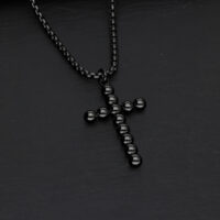 Schwarze Kreuzkette mit Kugeldesign auf dunklem Hintergrund
