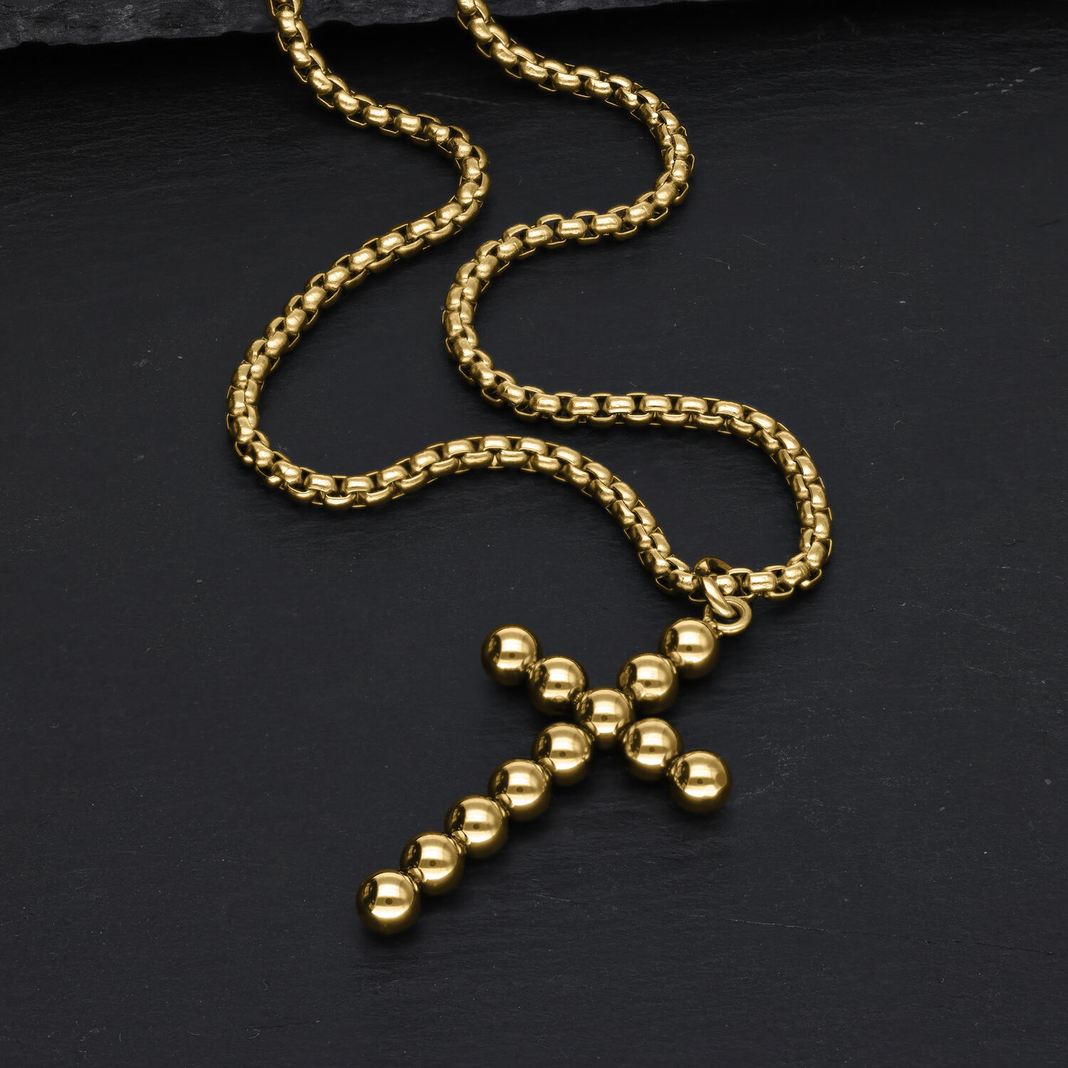 Goldene Kreuzkette aus Kugeln auf schwarzem Hintergrund