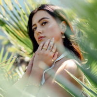 Goldene Little Petticoat Hoops im Freien Junge Frau trägt goldene Little Petticoat Hoops, umgeben von grünen Blättern