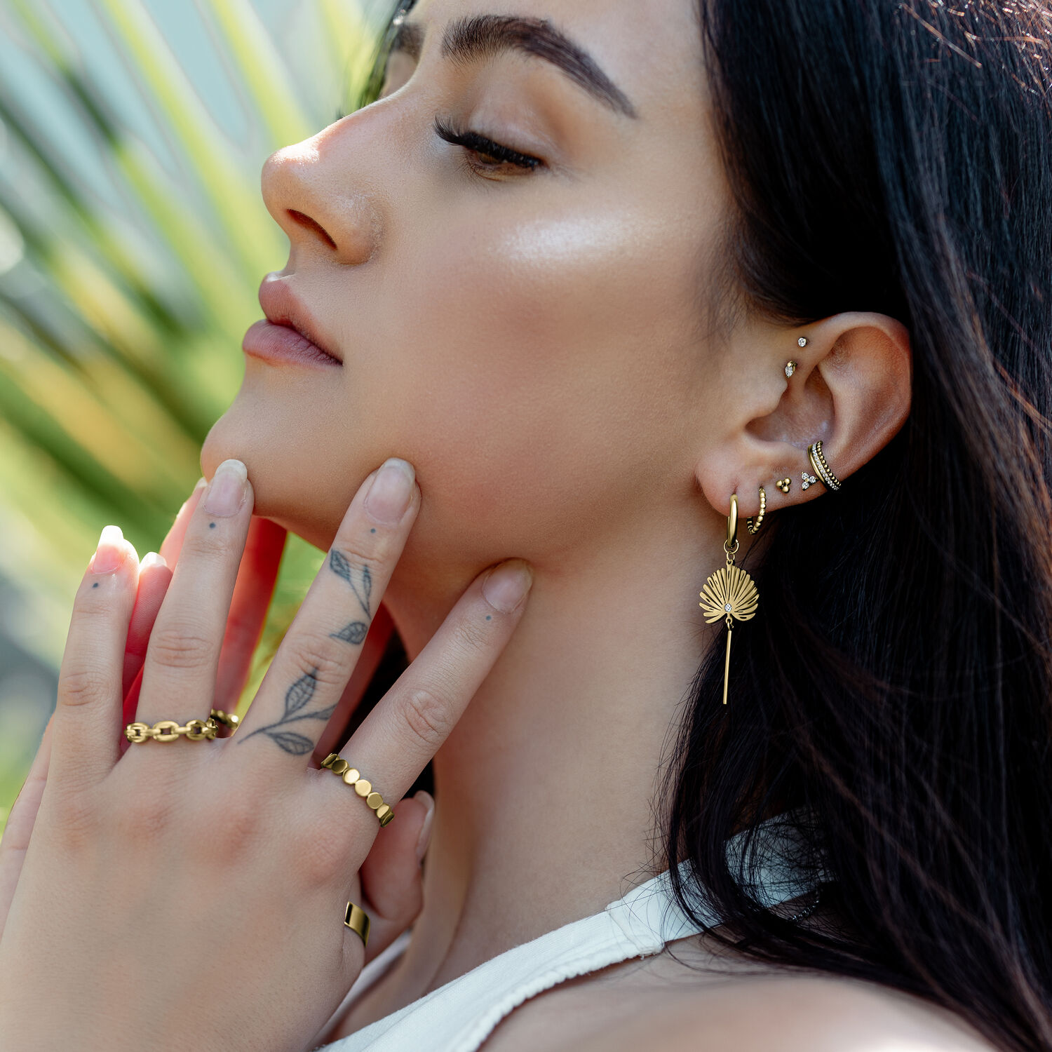 Goldene Little Petticoat Hoops im Ohr Frau trägt goldene Little Petticoat Hoops mit weiteren goldenen Accessoires