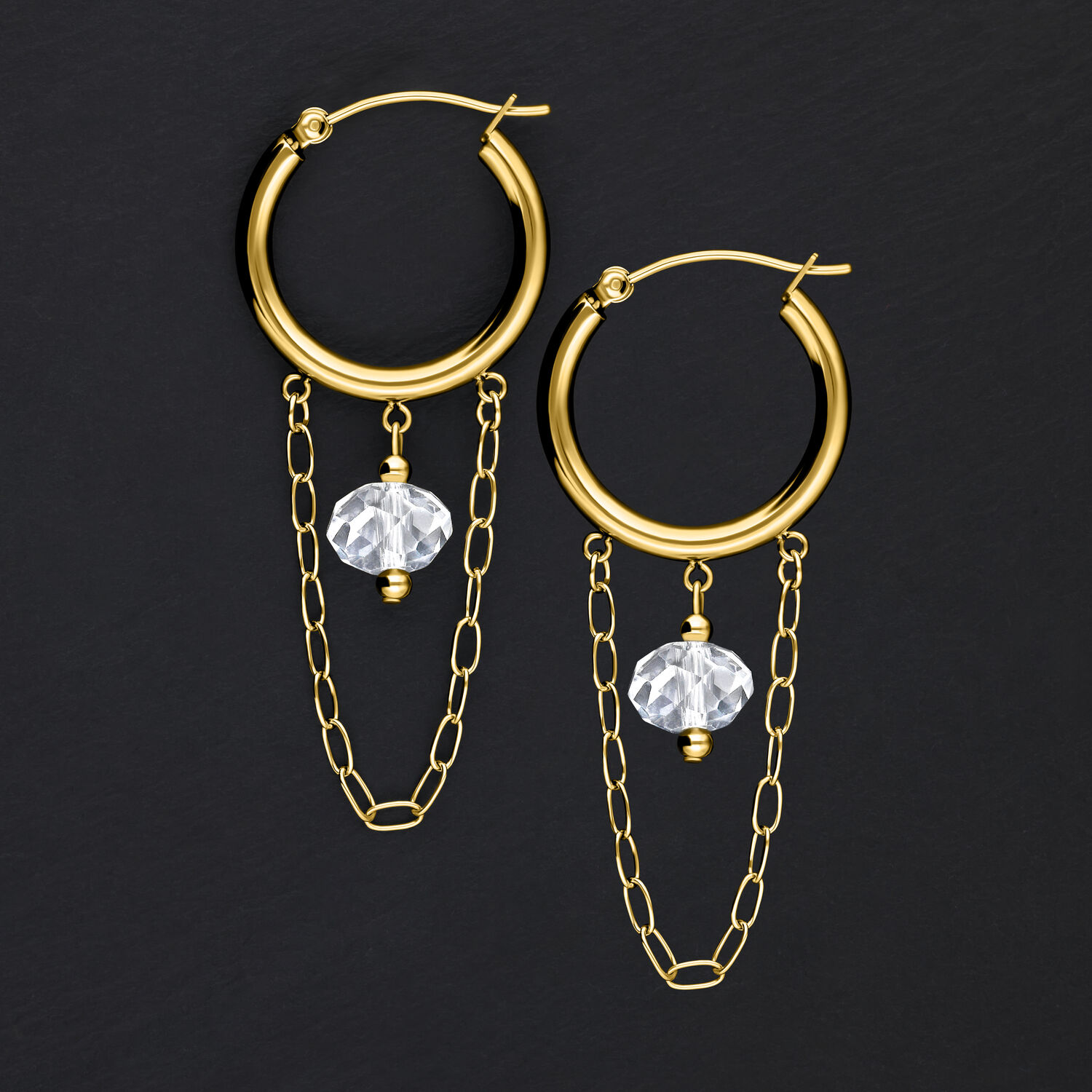 Goldene Metallohrringe mit weißen Steinen und Ketten auf schwarzem Hintergrund