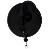 Schwarzer Ohrring mit Muschel und Perle, auf schwarzem Ohrmodell präsentiert