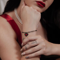 Schwarzes Sacred Heart Armband am Handgelenk Frau mit schwarzem Sacred Heart Armband aus Chirurgenstahl auf hellem Hintergrund