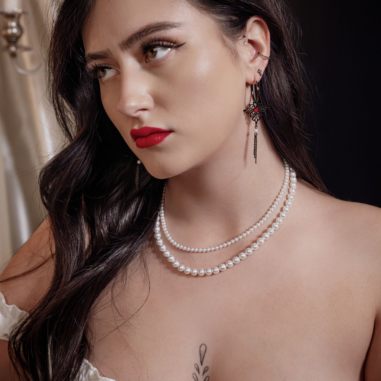 Frau mit schwarzen Sacred Heart Emaille Hoops Ohrringen und Perlenkette