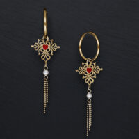 Goldene Creolen mit rotem Herzanhänger und Perlendetails vor schwarzem Hintergrund