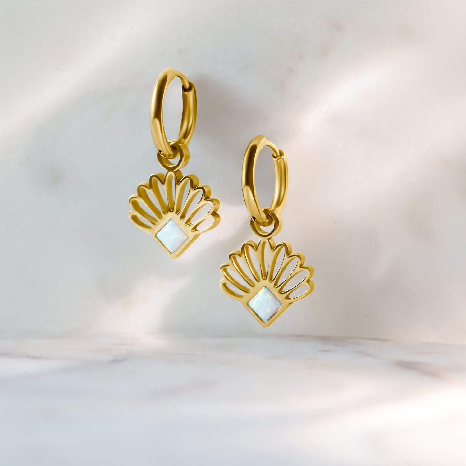 Goldene Opal-Fan-Creolen aus Chirurgenstahl Zwei goldene Creolen mit opalartigem Lüfterdesign auf hellem Hintergrund