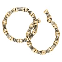 Kaksi kultaista Bonechain-korvapainoa kirurginteräksestä valkoisella taustalla