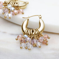 Goldene Glamour Hoops Ohrringe mit bunten Kristallen auf hellem Hintergrund