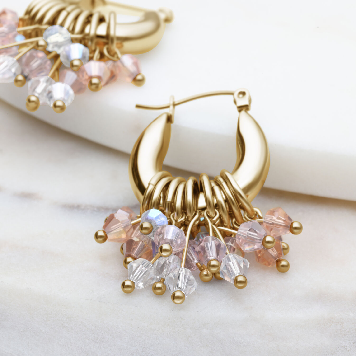 Goldene Glamour Hoops Ohrringe mit bunten Kristallen auf hellem Hintergrund