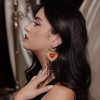 Goldene Herz-Ohrringe mit Stacheldraht-Design Goldene Herz-Ohrringe mit Stacheldraht in Ohr einer Frau mit dunklem Haar