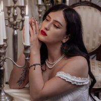 Schwarze Sacred Heart Hoops am Ohr einer Frau Frau mit schwarzen Sacred Heart Hoops Ohrringen in eleganter Umgebung