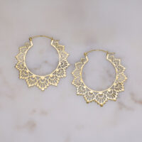 Goldene Creolen in Sonnenblumen-Design auf hellem Hintergrund