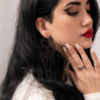 Schwarze Sun Moon Creolen aus Chirurgenstahl Frau mit langen schwarzen Haaren trägt schwarze Sun Moon Creolen auf weißem Hintergrund