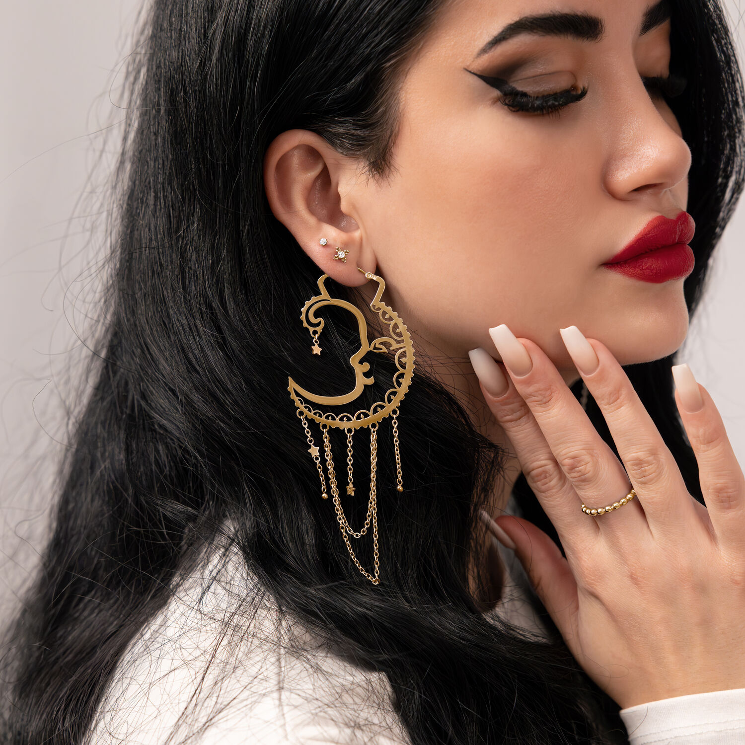 Frau mit goldenen Oldschool Sun Moon Hoops Ohrringen vor neutralem Hintergrund