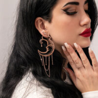 Frau mit Roségold-Ohrringen im Sun Moon Design vor neutralem Hintergrund