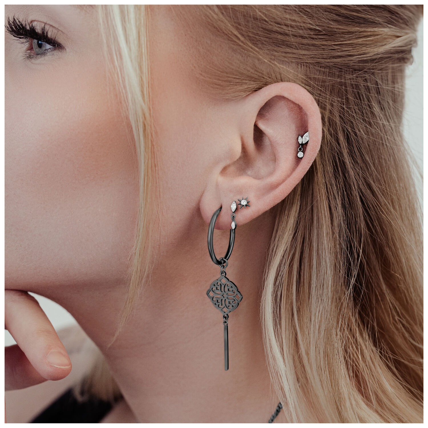 Schwarze Clover Hoops Ohrringe aus Chirurgenstahl am Ohr einer Frau