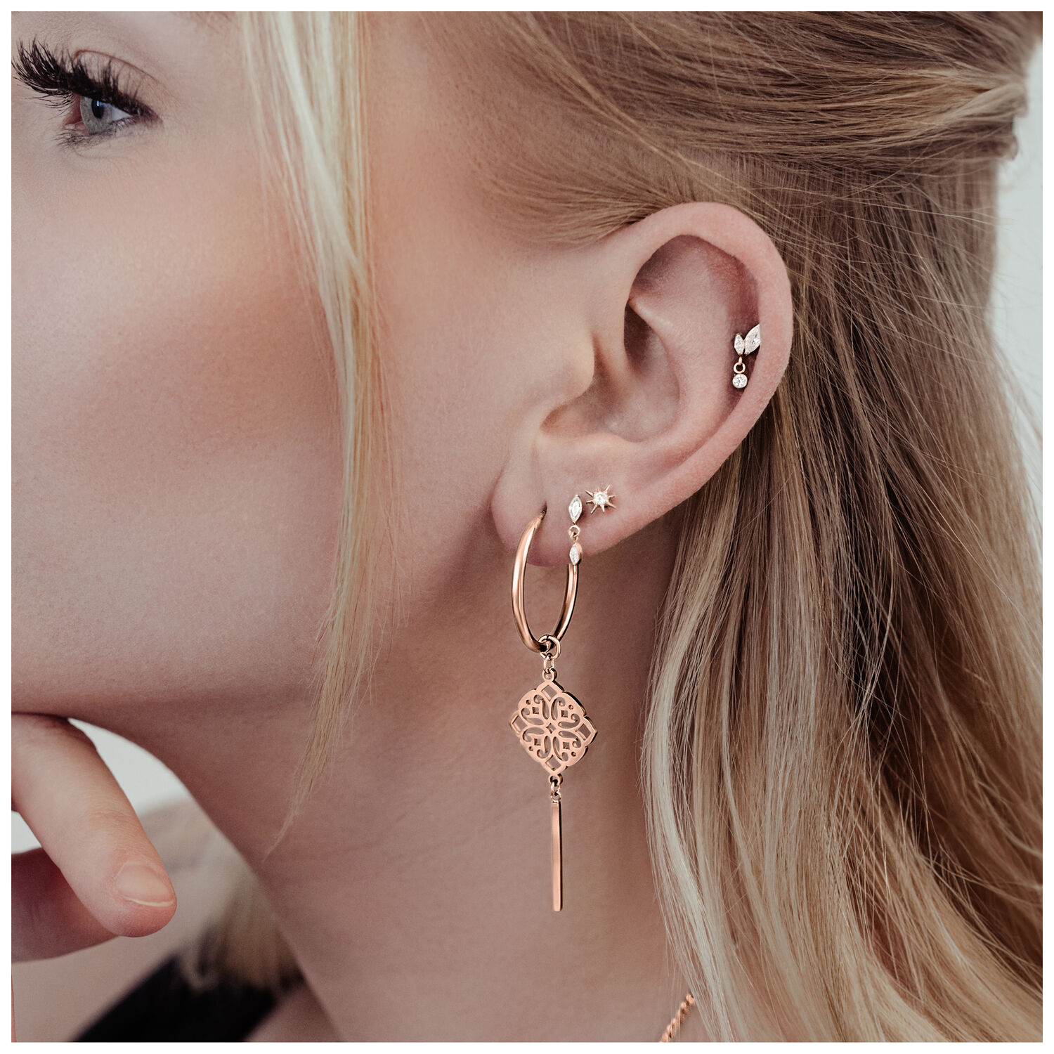 Frau mit roségoldenen Clover Hoops Ohrringen aus Chirurgenstahl, getragen am linken Ohr