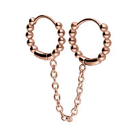 Kaksi rosékultaista Huggie-lävistysrengasta yhdistettynä ketjulla ja palloilla valkoisella taustalla