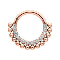 Ruusuinen kultainen clicker-lävistys kirkkailla kristalleilla valkoisella taustalla