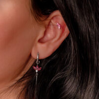 Hopeinen korvakoru punaisilla baguette-muotoisilla kristalleilla henkilön korvassa