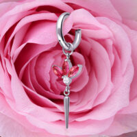 Hopeinen korvakoru punaisilla kristalleilla, kukkamuoto, vaaleanpunaisen ruusun edessä