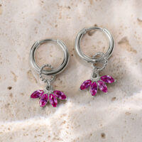 Hopeiset korvakorut vaaleanpunaisilla kristalliriipuksilla vaalealla kivipinnalla