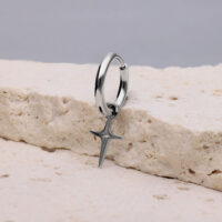 Hopeinen korvakoru, jossa on polaritähtimuotoinen riipus vaalealla kivellä