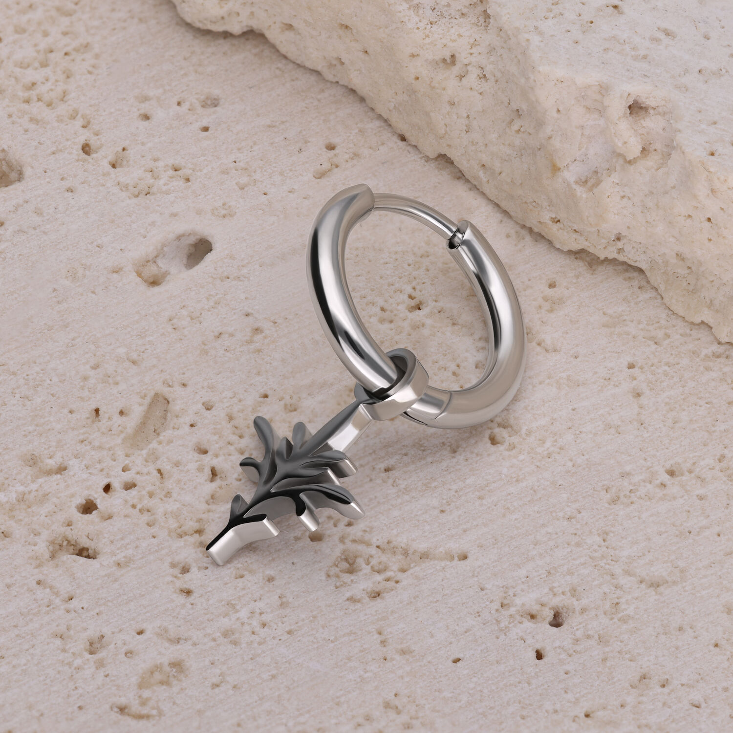 Hopeinen rengaskorvakoru mustalla oksanmuotoisella riipuksella vaalealla kivellä