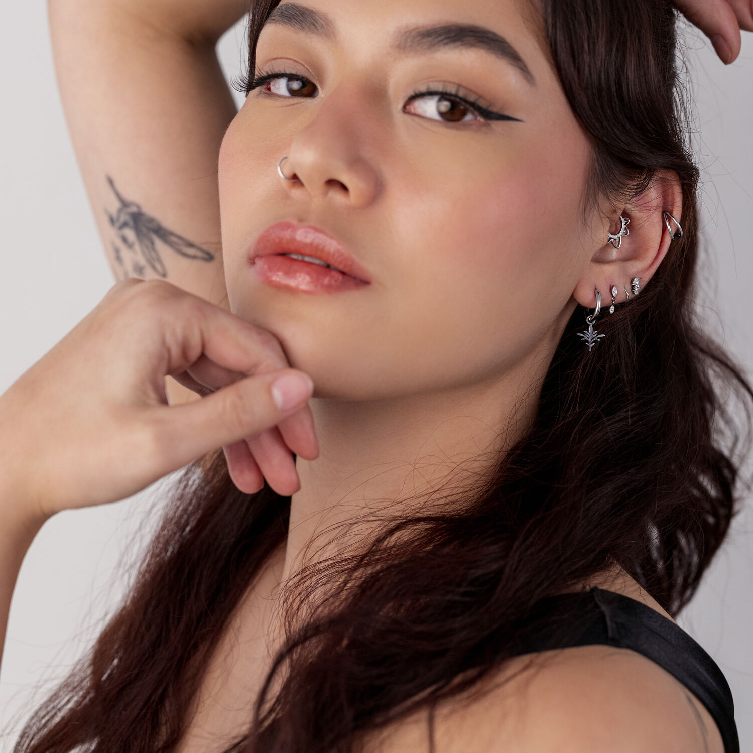 Pitkähiuksinen nainen käyttää Mini Branch -korvakoruja kirurginteräksestä, useita lävistyksiä ja tatuointeja näkyvissä.