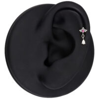 Hopeinen korvakoru punaisella kristallilla ja ovaalilla riipuksella, esitetty mustalla korvamallilla.