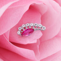 Hopeinen lisäosa, jossa on ovaali punainen kristalli vaaleanpunaisella terälehdellä