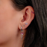 Korva, jossa useita lävistyksiä, mukaan lukien hopeinen Clicker punaisilla kristalleilla.