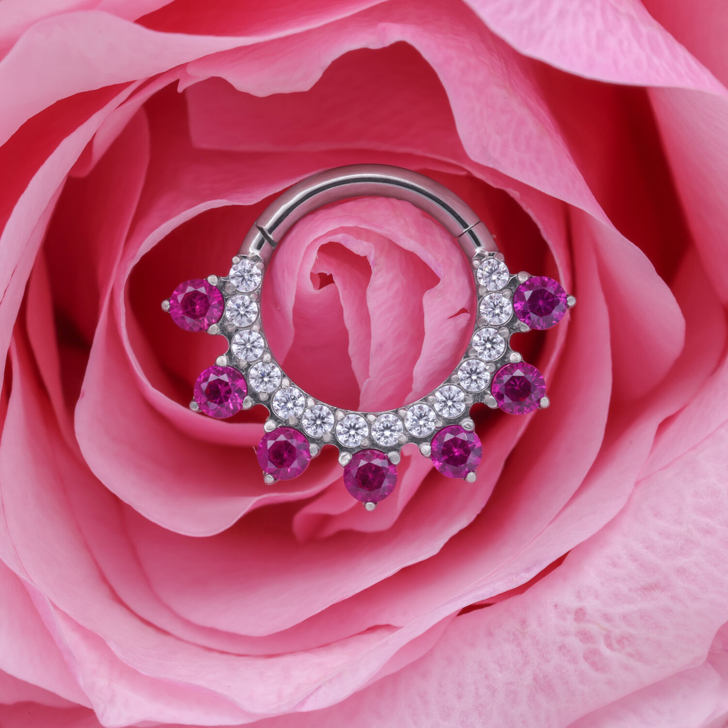 Hopeinen lävistysrengas punaisilla kristalleilla vaaleanpunaisella ruusunkukalla